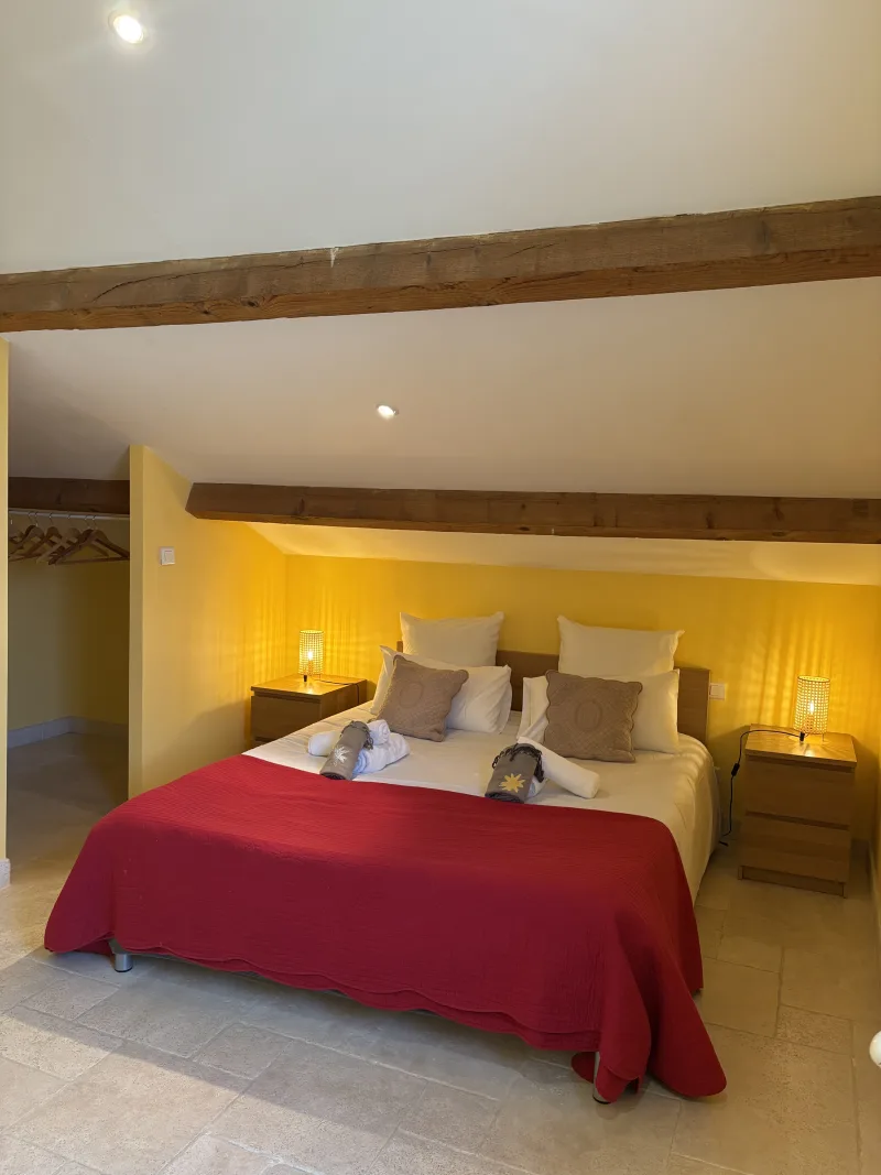 Chambre double au mur jaune avec poutres apparentes