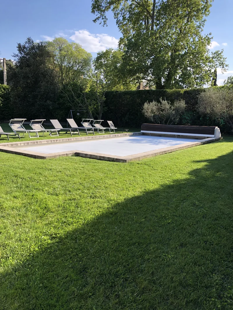 Piscine couverte bordée de chaises longues et d'oliviers